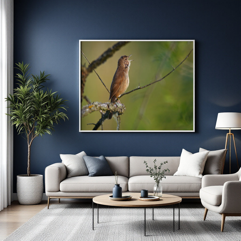 A framed wall art print showing a brown bird perched on a branch against a soft green background, displayed above a light gray sofa in a modern living room with a dark blue wall, potted plant, and coffee table.