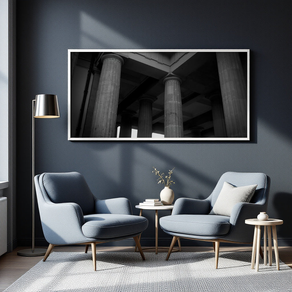 A modern living room scene with two light blue armchairs, a small round side table, a floor lamp, and a large framed black-and-white architectural wall print above them.