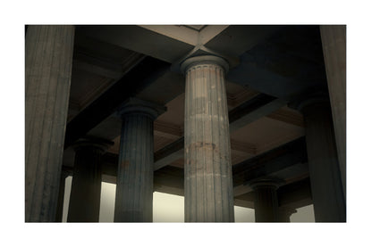 A photograph of classical stone columns and a coffered ceiling inside a grand building, framed with a white border.