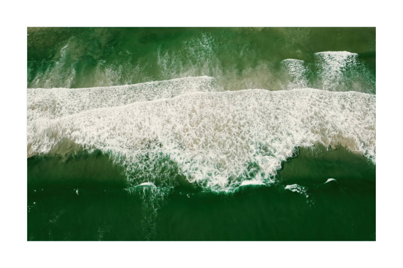 An aerial photograph of ocean waves with dark green water and white foam, presented as a square print with a white border.