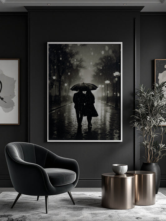 A framed black and white art print depicting a couple under a rain umbrella walking down a wet street, displayed on a dark charcoal wall in a modern living room setting with a black armchair, metallic side tables, and a potted plant.
