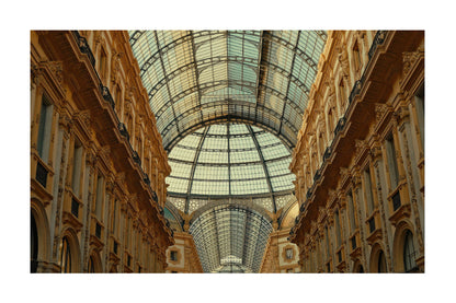 An architectural photograph of a grand glass-domed gallery with ornate beige and gold-toned stone columns on both sides, shown centered on a white background.