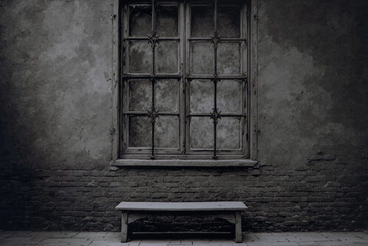 A dark, moody photograph of an old, weathered wooden window with iron bars set into a textured stucco and brick wall, with a simple wooden bench on the floor below.