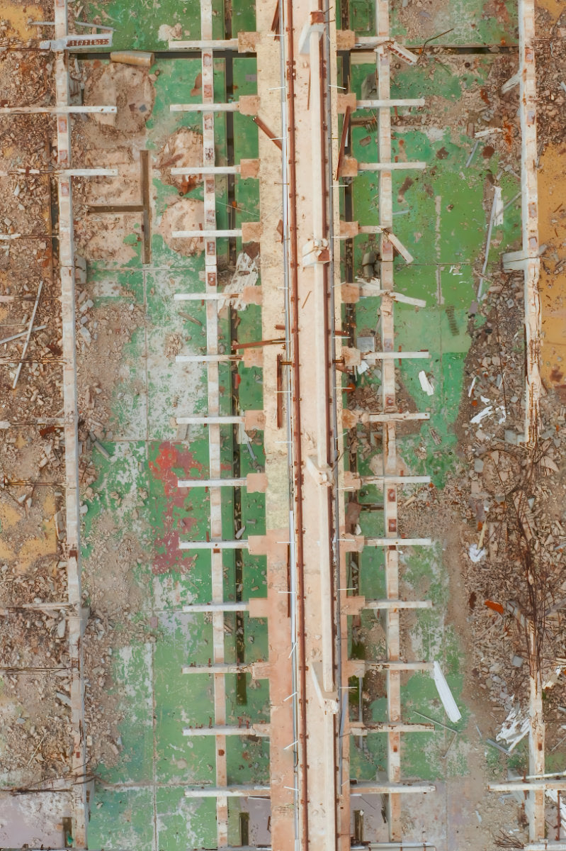 Aerial view of a construction site showing concrete forms, wooden support beams, and a green painted floor covering.