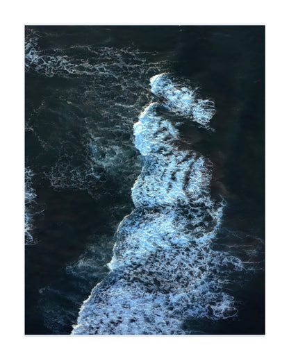 An aerial photograph of ocean waves with white foam breaking against dark blue water, presented as a square art print with a white border.
