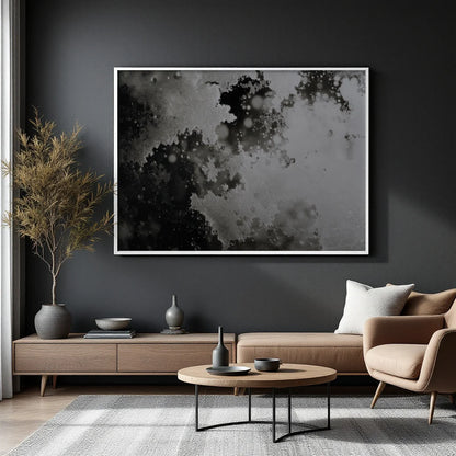 A large framed abstract black and white print hangs on a dark charcoal wall above a modern living room setup with a sofa, armchair, coffee table, and dried plant.