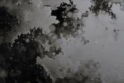 Abstract black and white textured background with frosted, crystalline splatter patterns and soft circular bokeh highlights.