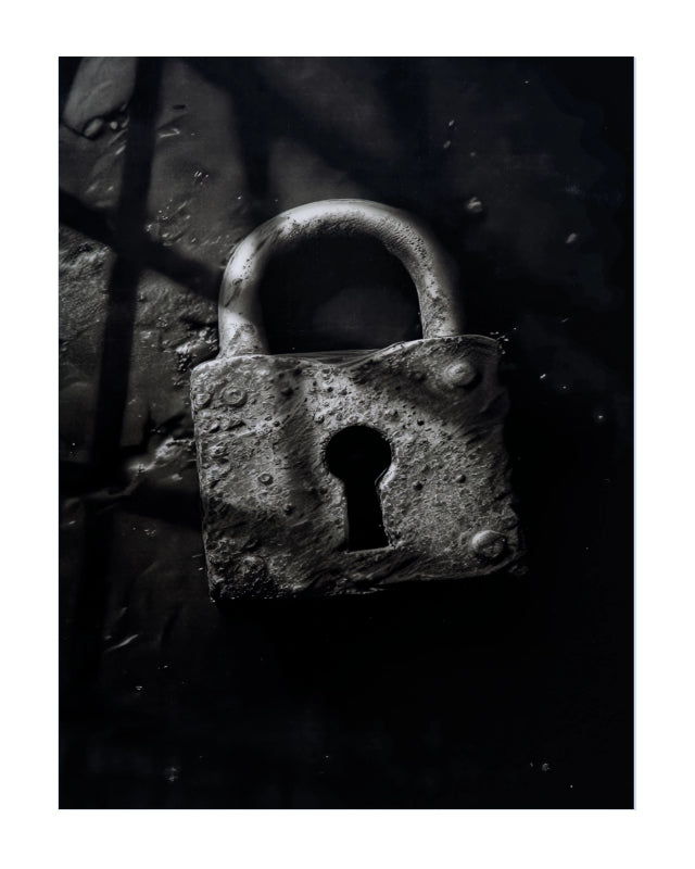 A close-up photograph of a weathered metal padlock with a textured, rusted surface, set against a dark, shadowed background.