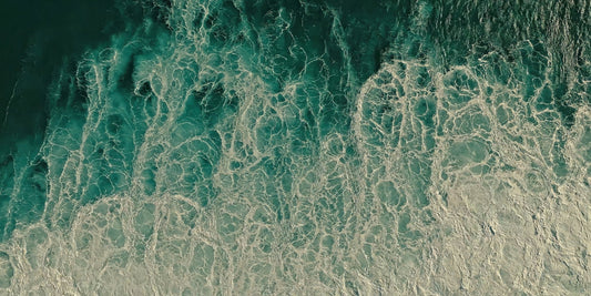 Aerial view of ocean waves with turquoise water and white sea foam, filling the entire frame.