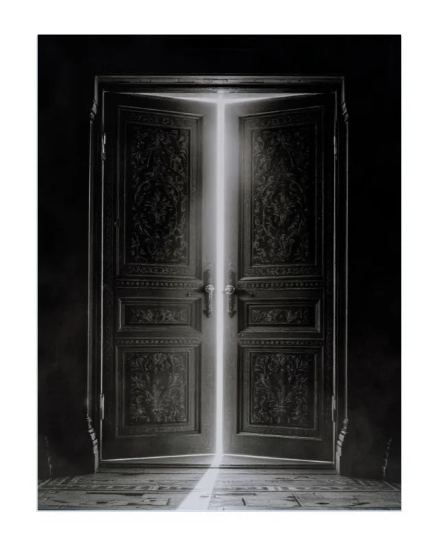 A black and white art print depicting ornate double doors with a bright beam of light shining through the center, casting a reflection on the floor.