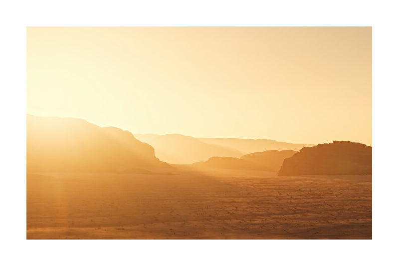 A warm desert landscape print featuring layered mountains and a flat foreground bathed in golden sunlight, with a white border around the artwork.