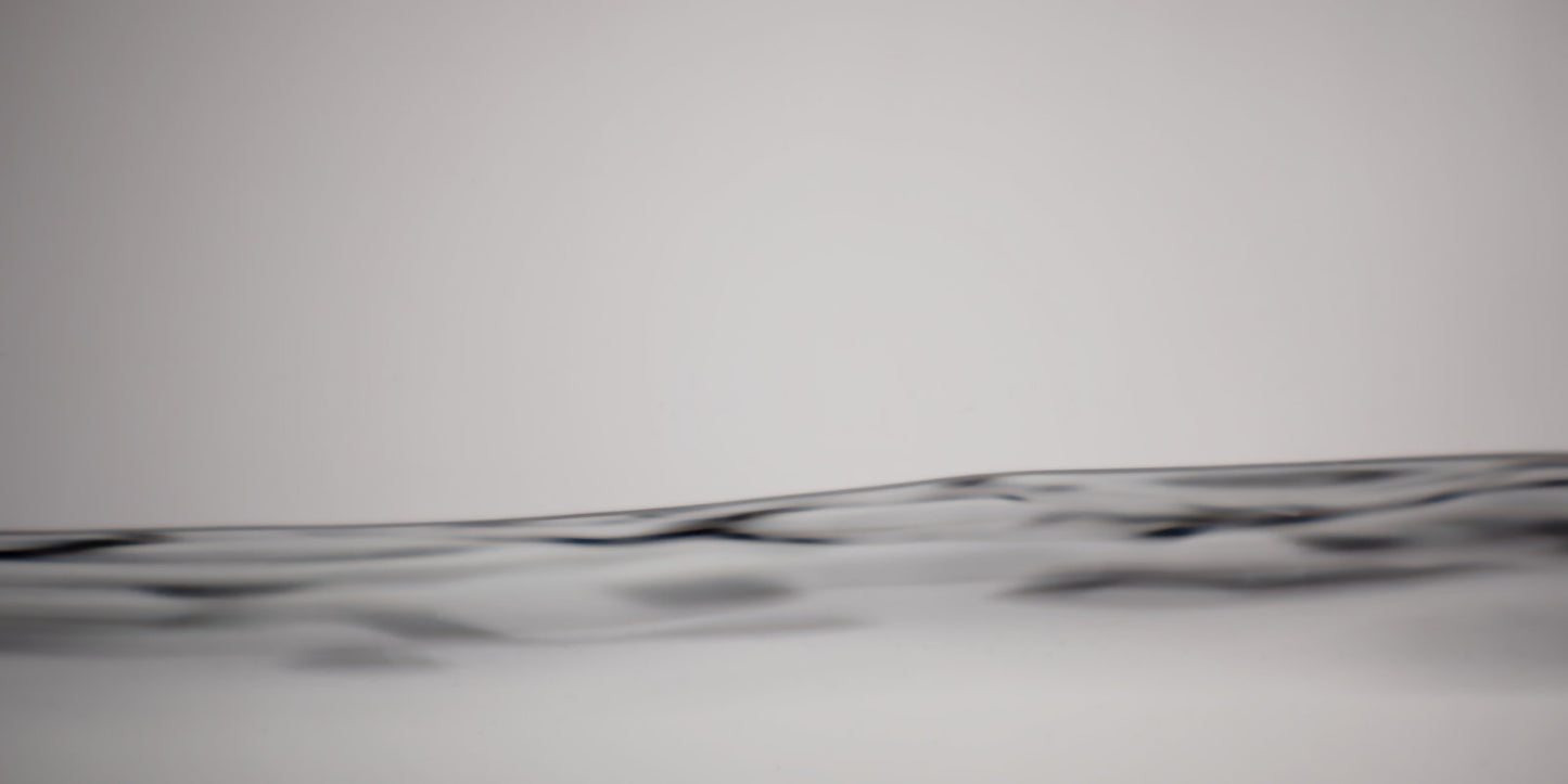 A close-up abstract view of a dark wavy horizontal line or band across a light gray background.