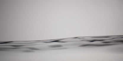 A close-up abstract view of a dark wavy horizontal line or band across a light gray background.
