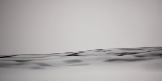 A close-up abstract view of a dark wavy horizontal line or band across a light gray background.