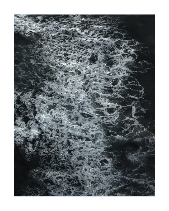 An aerial photograph of dark water with dense white sea foam, presented as a square art print with a white border.